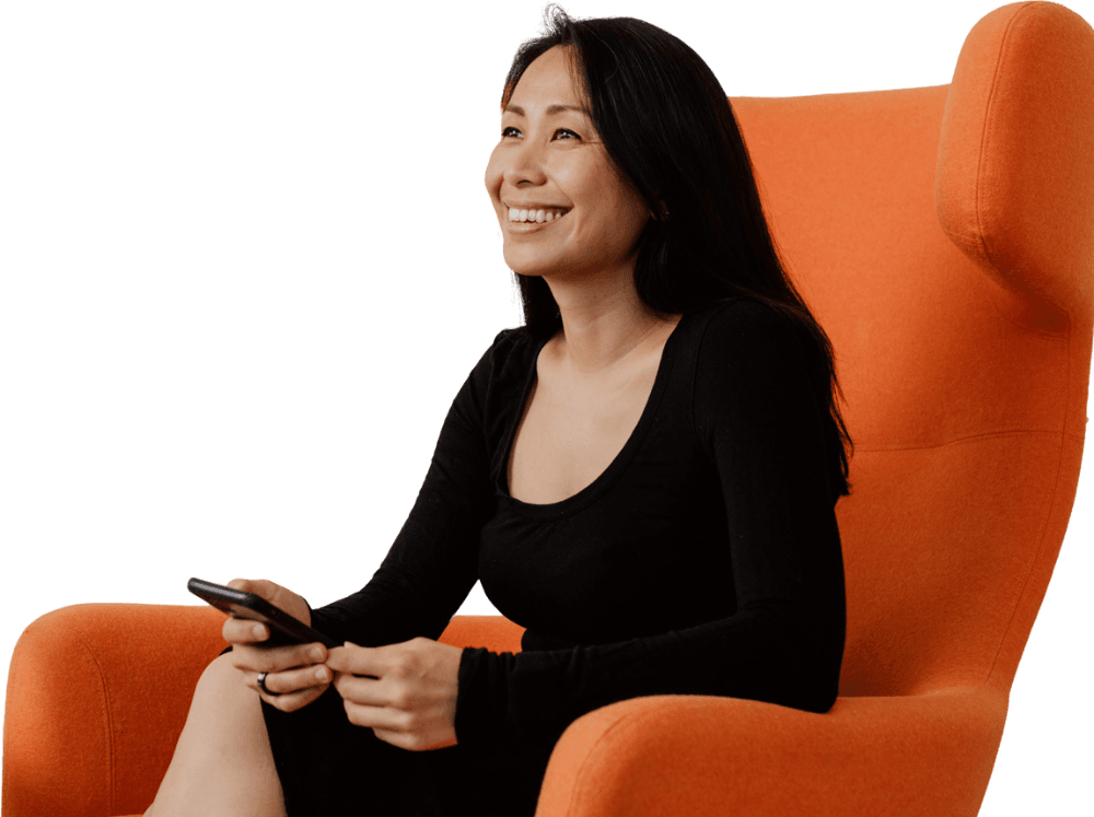 Audrey Tsang seated in an armchair, leaning forward and smiling